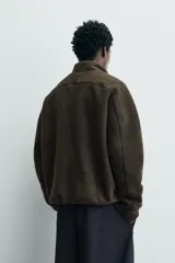 Sudadera de corte relajado confeccionada en tejido con efecto borreguillo, con cuello subido, cierre frontal de cremallera y bolsillos de vivo en la cadera. Presenta mangas largas con puños elásticos y acabados con cinta elástica.