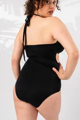 Malla entera negra con escote strapless, breteles finos al cuello y espalda recta. Presenta aberturas en el abdomen unidas por aros metálicos.