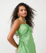 Vestido corto verde de lino con tirantes finos ajustables, escote halter con lazo y cutouts laterales con lazos.