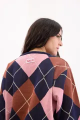 Sweater holgado de tejido de punto con patrón de rombos en tonos azul marino, rosa y marrón, con detalles de líneas en lurex. Presenta cuello redondo y mangas largas.