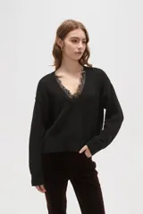 Sweater negro de punto con escote en V profundo y detalle de encaje en el borde del cuello. Presenta mangas largas con puños acanalados y un corte holgado.