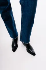Bota de caña media estilo western, confeccionada en cuero negro con paneles laterales elásticos texturizados y taco cuadrado.