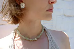 Collar tipo choker compuesto por piedras naturales de cuarzo lima en forma de chips irregulares, con un dije central de bronce macizo. El diseño es ajustable y versátil, permitiendo su uso también como pulsera.