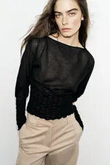 Jersey de punto semitransparente color crudo, con cuello redondo, manga larga y detalles elásticos de nido de abeja en el torso y en los puños.
