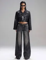 Campera corta de cuero sintético negro con cierre cruzado, cuello con solapas y cinturón con hebilla.