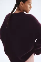 Buzo de punto oversized color morado oscuro, con textura suave y peluda, cuello redondo y hombros caídos.