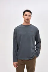 Remera manga larga de algodón lavado con textura suave, color gris oscuro, con estampado pequeño en el pecho y estampado en la manga.