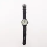 Reloj de pulsera con correa símil cuero negra y esfera blanca con números arábigos.