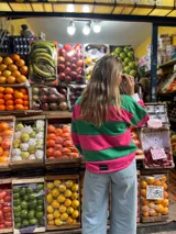Sweater a rayas horizontales rosas y verdes, con cuello polo blanco y puños blancos.