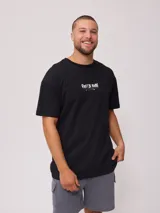 Remera blanca de algodón con estampado en la espalda que incluye un sol con un surfista en el centro, texto y motivos playeros.