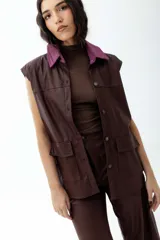 Chaleco marrón de cuerina con cuello de pana color lila, con bolsillos frontales y cierre con botones.