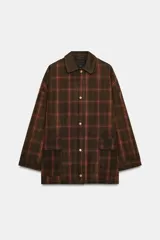 Chaqueta de mujer de la colección Zara Woman, confeccionada en algodón 100% con acabado encerado. Presenta un estampado a cuadros en tonos marrón y rojo, cuello solapa de pana, manga larga con puño y botón, bolsillos de plastrón con solapa en el delantero y cierre frontal con botones a presión.