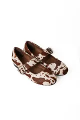 Chatas de cuero con estampado animal print marrón y blanco, con correa sobre el empeine y hebilla metálica.