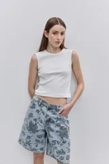 Bermuda de jean de calce amplio y largo a la rodilla, con estampado floral oscuro sobre fondo de mezclilla celeste. Cuenta con cinco bolsillos, trabillas para cinto y cierre frontal con botón y cremallera.