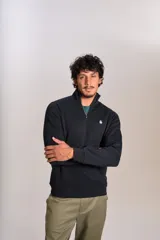Buzo de cuello alto con cierre frontal parcial, manga larga y puños acanalados. Presenta un diseño liso en color negro con el logo de la marca bordado en el pecho.