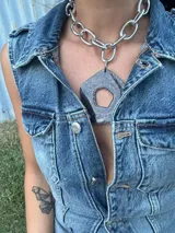 Collar con cadena gruesa plateada y dije abstracto de acrílico y resina color blanco. El dije es desmontable.