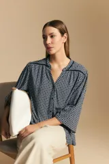 Camisa de manga larga con silueta relajada, estampado geométrico en blanco y negro, escote abierto con botones frontales y puños elastizados.