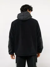 Campera de polar con capucha, cierre frontal completo y diseño en bloques de color azul y azul marino. Presenta detalles en nylon en la zona del cierre y la capucha, con logo de la marca aplicado en el pecho.