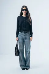 Cardigan negro de punto fino, con cuello redondo, cierre frontal de botones y mangas largas con puños ajustados.