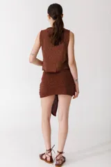 Falda corta roja de tejido de punto con diseño cruzado y lazo lateral.