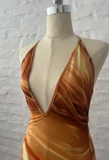 Vestido corto con estampado abstracto en tonos naranja, blanco y marrón. Diseño con escote halter y espalda descubierta.