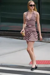Vestido corto confeccionado en hilatura con mezcla de algodón, con diseño a rayas horizontales en color rosado y marrón. Presenta cuello halter con lazada, escote en pico, cuerpo fruncido y bajo acabado en volante.