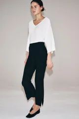 Pantalón de tiro alto con diseño cropped, confeccionado en tejido con viscosa. Presenta raya planchada frontal, aberturas laterales en el bajo y cierre lateral con cremallera oculta.