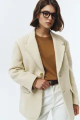 Blazer de lana con mezcla de alpaca en color beige, con cuello sastre, cierre frontal de dos botones y bolsillos laterales con solapa. Presenta una textura suave y vellosa.