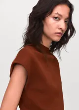 Jersey de punto fino color marrón, con cuello perkins y mangas cortas. Presenta un diseño entallado y minimalista.