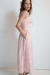 Vestido midi de popelina blanco con estampado de lunares rojos, escote corazón, tirantes finos con lazo y detalle de nudo en el busto.