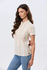Camisa de lino de manga corta con cuello mao y cierre frontal parcial con botones. Presenta un diseño de rayas verticales en tonos suaves como rosa, verde, celeste y beige.
