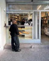 Sweater negro de punto con cuello redondo y corte holgado. Diseño con motivo de zurcido en la manga izquierda.