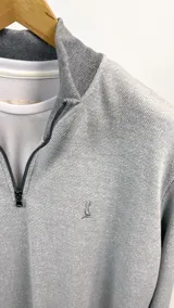 Buzo de algodón de punto color gris con medio cierre frontal y cuello alto.