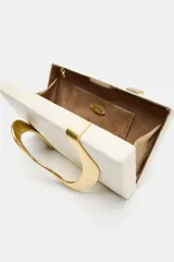 Cartera tipo clutch de color beige con solapa, cierre imantado y detalle metálico dorado con diseño curvo en el frente. Cuenta con bolsillo interior y correa de cadena metálica opcional.