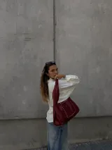 Cartera tipo hobo de cuero color bordó con tachas plateadas. Tiene cierre con pastillas imantadas, sobre interno grande enganchado y bolsillo externo con pastilla imantada.