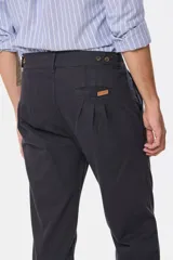 Pantalón de vestir color verde oliva, de corte recto, con bolsillos laterales y traseros. Se ajusta a la cintura con cinturón de cuero marrón.