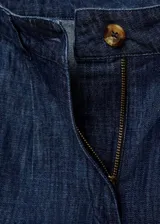 Short de denim azul con tiro medio, trabillas, cierre frontal con cremallera y botón, pinzas delanteras y bolsillos laterales.