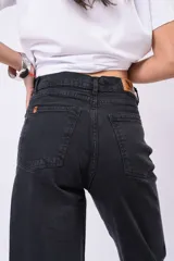 Pantalón wide leg de tiro alto confeccionado en denim negro, adornado con brillos de strass distribuidos por todo el frente.