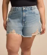 Short de jeans estilo boyfriend para tallas grandes, color celeste claro desgastado, con roturas y deshilachados en los bordes. Presenta cierre tradicional y trabillas en la cintura.