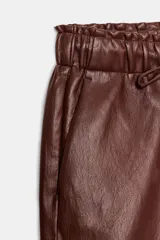 Pantalón de tiro alto confeccionado en material efecto piel, con cintura elástica ajustable mediante cordones, bolsillos delanteros y bolsillos de plastrón en la parte trasera.