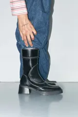 Botas negras de cuero vacuno con caña media y tacón bloque. Presentan puntera cuadrada, cierre interior y costuras blancas en contraste.