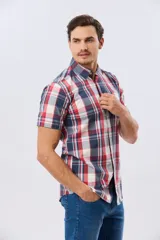 Camisa de manga corta con estampado de cuadros en tonos celestes, azules, blancos y verdes, con cierre frontal de botones y bolsillo ojal en el pecho.