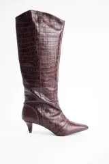 Bota de caña alta confeccionada en cuero vacuno con textura de reptil. Presenta un diseño de punta fina y un taco bajo tipo kitten heel.