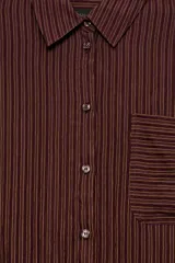 Camisa de corte oversize confeccionada en mezcla de viscosa, con diseño de rayas verticales, cuello solapa, manga larga con puños, bolsillo de plastrón en el pecho y cierre frontal con botones.