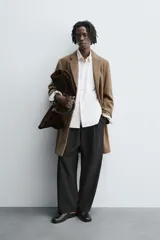 Abrigo de corte regular fit confeccionado en tejido compacto con mezcla de lana. Presenta cuello con solapas de muesca, cierre frontal de botonadura, bolsillos de vivo en la cadera y abertura central en la espalda.