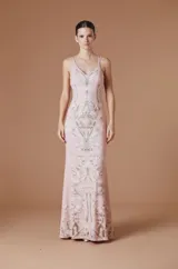 Vestido largo de Natalia Antolin con escote en V y breteles finos. Presenta un diseño ajustado en el torso que se ensancha suavemente hacia el ruedo, con un estampado botánico simétrico en tonos tierra sobre una base rosada.