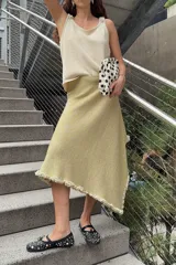 Chal de punto color dorado con acabado en lurex, de diseño amplio y asimétrico, con bordes decorados con volados artesanales.