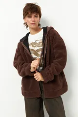 Campera tipo canguro marrón de tela teddy con capucha y cierre frontal. El forro es de felpa color negro y los puños son elastizados.
