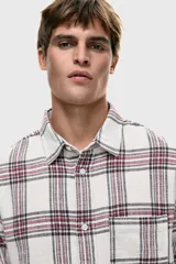 Camisa de franela de algodón suave con efecto lavado, de corte relajado y cuello inglés. Presenta un estampado a cuadros en blanco, rojo y negro, tapeta clásica de botones, un bolsillo superior abierto y canesú en la espalda. Tiene mangas largas con tapeta, puños abotonados y bajo levemente redondeado.