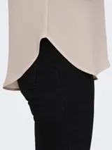 Blusa de corte recto y cuello redondo, con mangas cortas tipo casquillo. Presenta un diseño con cierre en la parte posterior y un largo ligeramente mayor en la espalda. Confeccionada en tejido suave de poliéster reciclado con elastano.